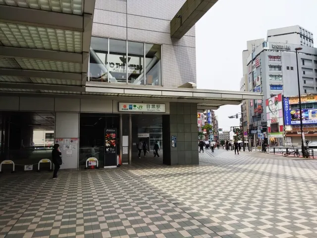 東京都目黒区の目黒駅前の様子。駅ビルの入口と周辺の街並みが映る日中の風景。